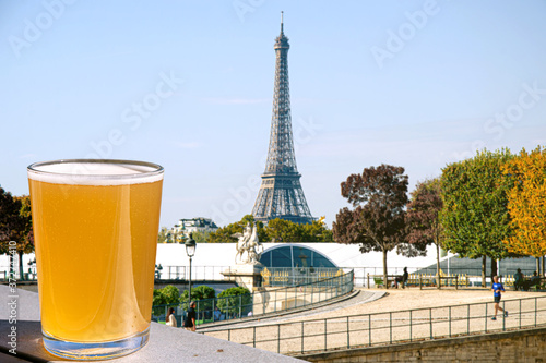Glass of light beer on Eiffel tower blur background. Sunny view of glass of red wine overlooking the Eiffel Tower in Paris, France