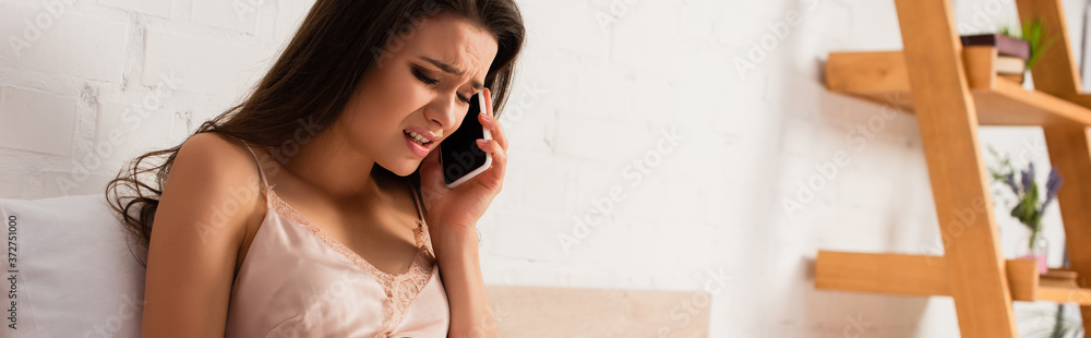panoramic crop of upset woman talking on smartphone in bedroom panoramic crop of upset woman talking on smartphone in bedroom