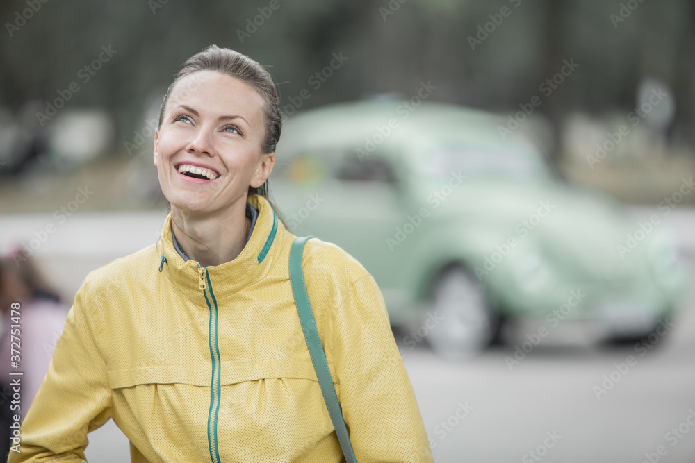 Excited young woman and her new car behind her. Young and cheerful woman enjoying new car and warm autumn or spring days Excited young woman and her new car behind her. Young and cheerful woman enjoying new car and warm autumn or spring days