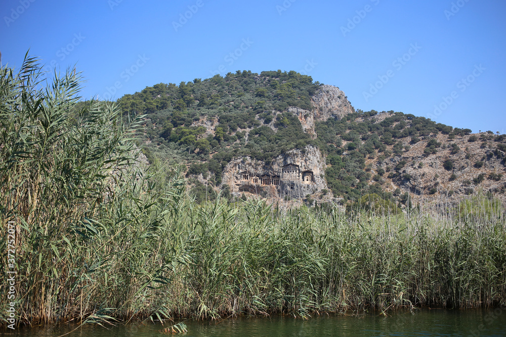 Travel along the Dalyan River in Turkey, view of the rocky Lycian tombs, and high reeds.