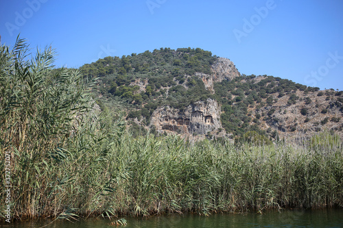Travel along the Dalyan River in Turkey, view of the rocky Lycian tombs, and high reeds.