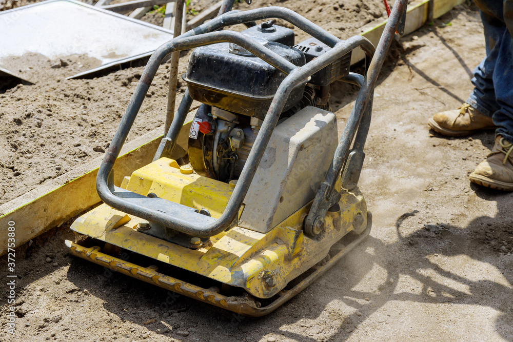 Vibratory plate compactor on a new pavement in a industrial construction machine
