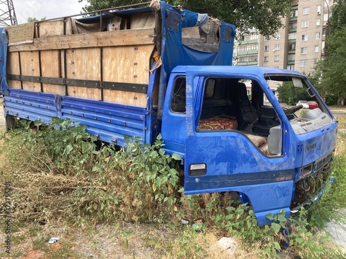 An abandoned blue truck stands in the middle of the grass