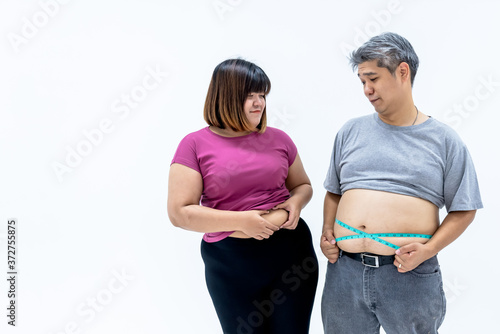 Portrait images of Asian couple, fat man and woman, are looking at each other's beelly fat, On white background, to fat people and health care concept. photo