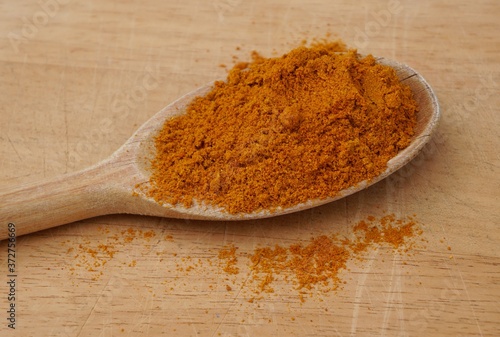 Curry powder on wooden spoon. Indian spice.

