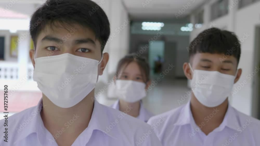 Slow motion of Asian students in a white uniform and wearing white masks are walking in the academy during the Coronavirus 2019 (Covid-19) epidemic. Slow motion of Asian students in a white uniform and wearing white masks are walking in the academy during the Coronavirus 2019 (Covid-19) epidemic.