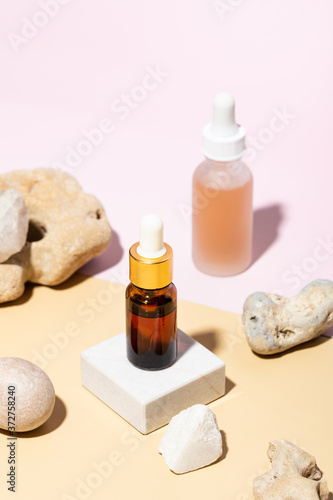 Brown and transparent bottles with cosmetic liquid on pastel background. Set design.
