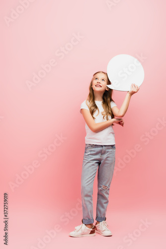 full length view of kid in white t-shirt and blue jeans looking up while holding thought bubble on pink © LIGHTFIELD STUDIOS