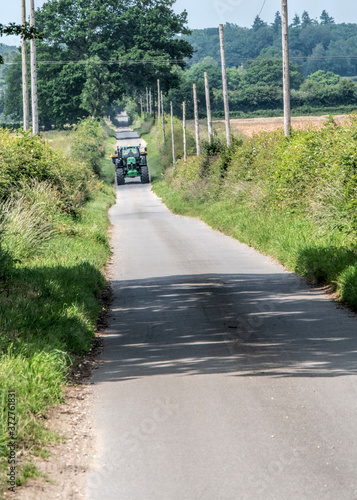 A typical norfolk rural road only just wide enough for the farmer and his tractor to drive up the road in england