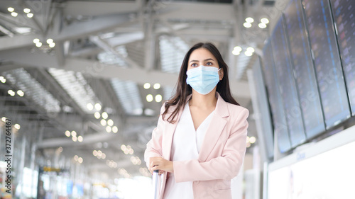 A business woman is wearing protective mask in International airport, travel under Covid-19 pandemic, safety travels, social distancing protocol, New normal travel concept