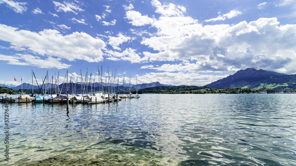 Moored boats on the beautiful Luzern lake in the middle of Swiss Alps with a blue and cloudy sky