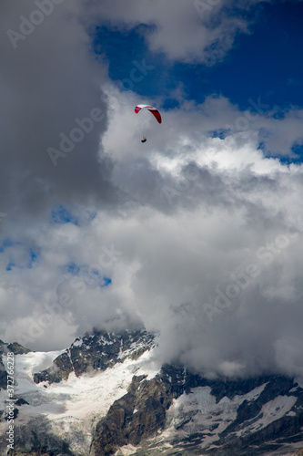 Zermatt, Switzerland; A paraglider sails over clouds and mountains near Matterhorn, Switzerland