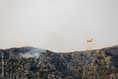 A fire fighting water bomber dropping water on a forest fire on top of the Kozjak mountain in Croatia. Summer wildfires are very common in the dry and warm area of meditarranean