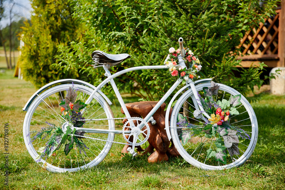 White bicycle decorated with flowers in bloom in rural