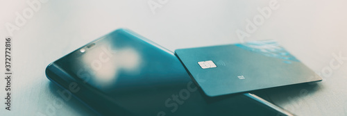 Online payment concept with mobile phone and credit card banner. Panoramic crop of a cellphone at home for shopping on tech app.