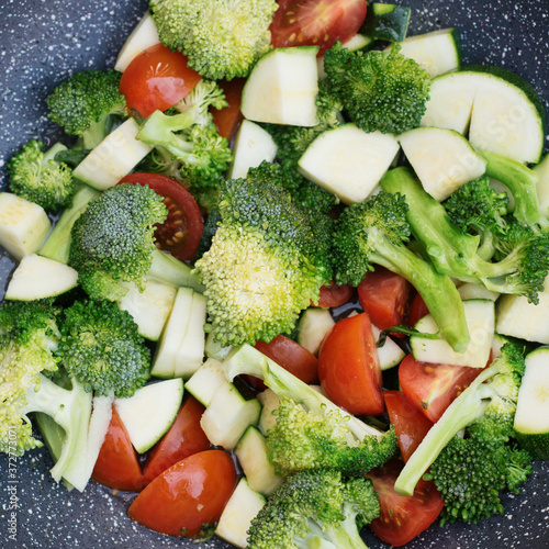 Green vegetables  broccoli  zucchini  tomatoes in a WOC pan
