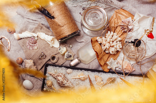 a lot of sea theme in mess like shells, candles, perfume, girl stuff on linen, pretty textured post card view vintage photo