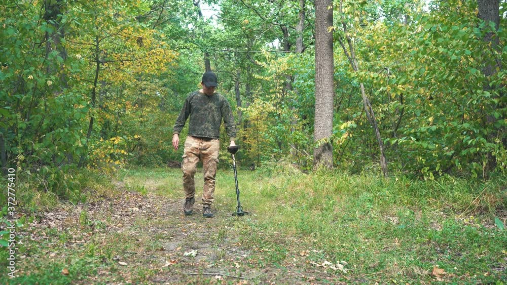 man walks through the woods with a metal detector man walks through the woods with a metal detector