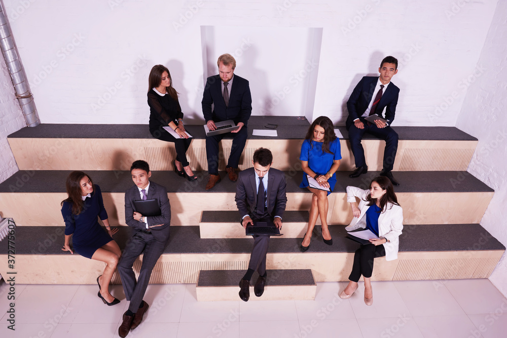 Multi ethnic group of people are working with laptop computers, digital tablet and paper documents during their joint studies in the School of Business. Young smart students are using modern devices