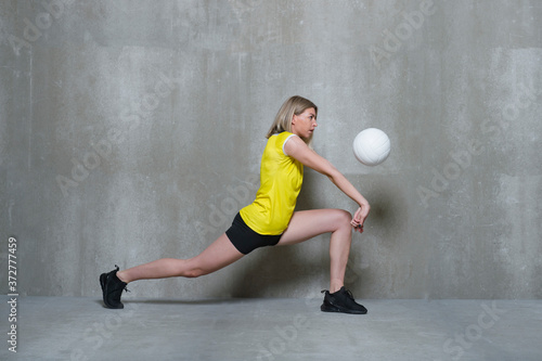 Young woman volleyball player on gray background. Workout online concept