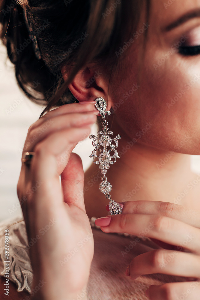 
bride tries on earrings