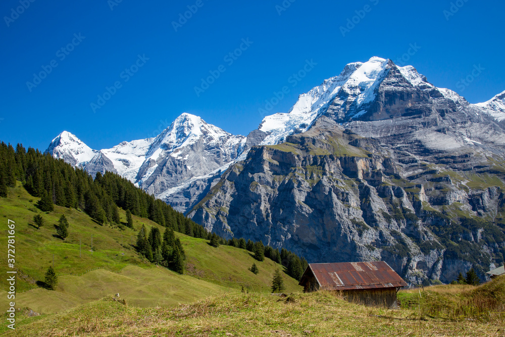 A typical alpine chalet along the Eiger trail. Eiger, Monch and Jungfrau mountains are in the background.