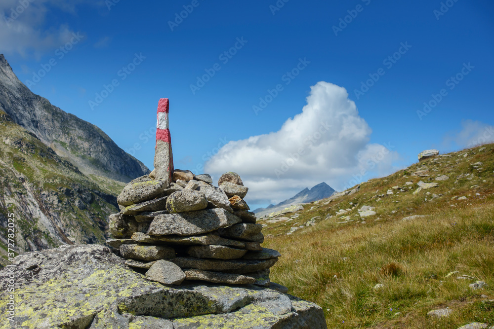 Wegmarkierung und Wegweiser auf einem Steinturm an einem Wanderweg in Tirol Wegmarkierung und Wegweiser auf einem Steinturm an einem Wanderweg in Tirol