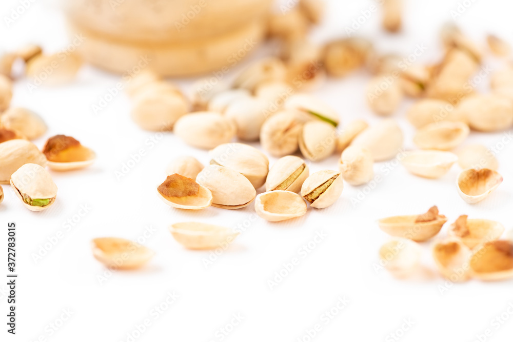 Peeled pistachios in mortar on a white background