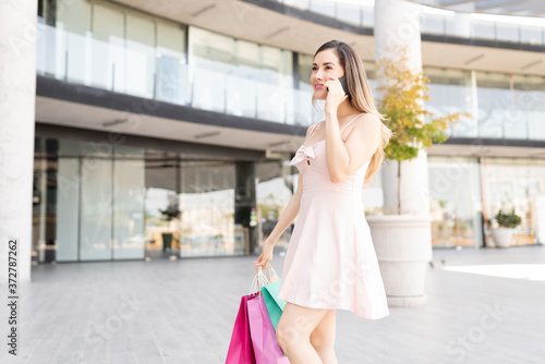 Smiling Woman With Shopping Bags Talking On Smartphone