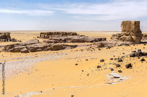 View over a sandy plain with isolated rock formations  Chad