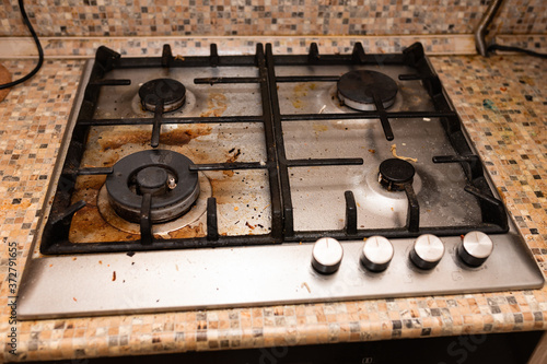 Dirty gas stove stained while cooking, a stove in grease. Unsanitary conditions, a mess in the house.