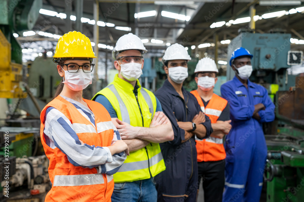 Portrait of confident engineer woman. Diverse multiethnic worker wearing surgical mask in manufacturing factory on day covid-19 virus pandemic. New normal, epidemic prevention. Selective focused Portrait of confident engineer woman. Diverse multiethnic worker wearing surgical mask in manufacturing factory on day covid-19 virus pandemic. New normal, epidemic prevention. Selective focused