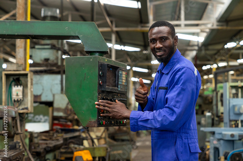 Portrait of smiling african american factory worker showing thumb up. Technician engineer control machines in the workplace on a business day. Concept of Industrial manufacturing.