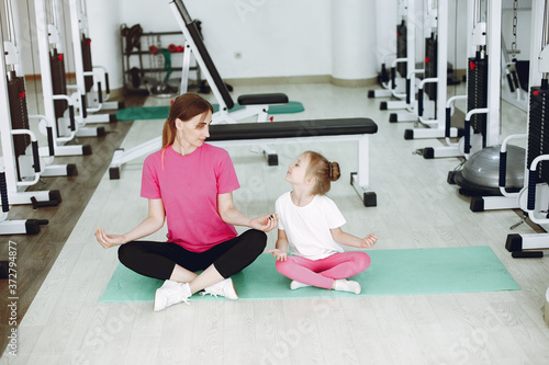 Mother with daughter in a gym. Little girl are engaged in gymnastics