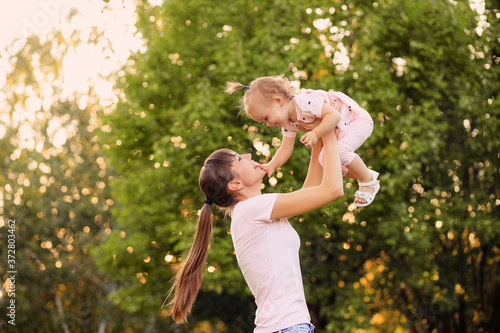 Happy family, mother and daughter are playing and laughing in nature in the park