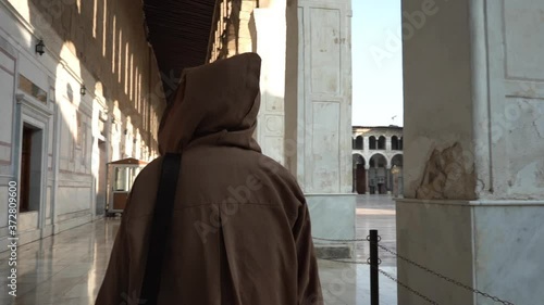 Person in Monk Tunic WIth Hoodie Walking in a Exterior of Umayyad Grand Mosque. Damascus Syria. Slow Motion photo