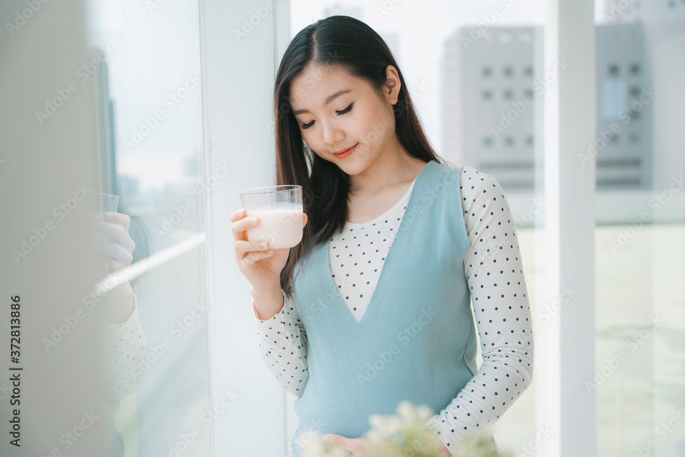 Young beautiful pregnant asian woman holding a cup of milk. Young beautiful pregnant asian woman holding a cup of milk.