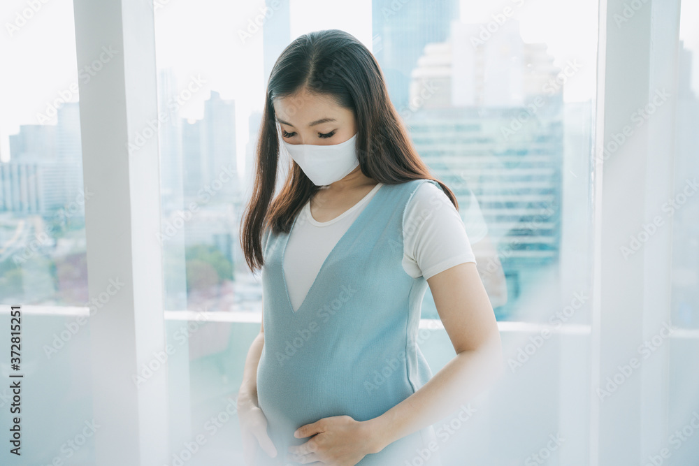 Beautiful pregnant asian woman wearing mask quarantine at home.
