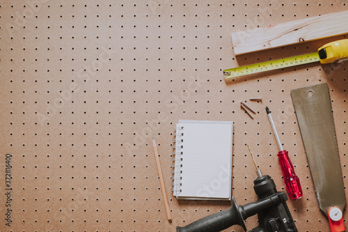 Top view of woodworking tools and notebook on pegboard background photo