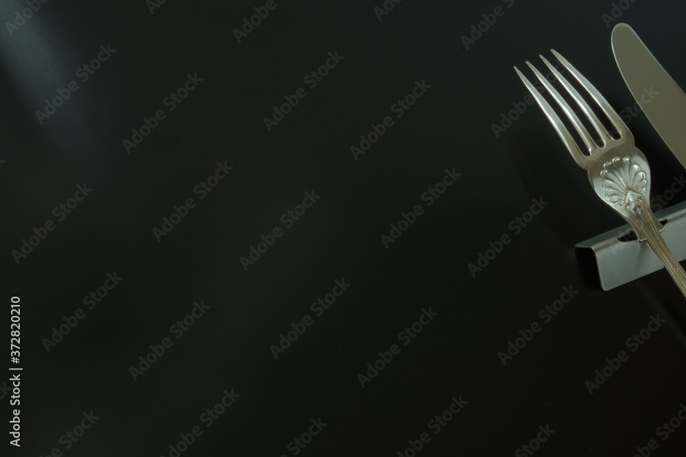 lay out antique expensive silver cutlery. knife , fork on the table . to shine in light. Top view photo of black background with copy space. lay out antique expensive silver cutlery. knife , fork on the table . to shine in light. Top view photo of black background with copy space.