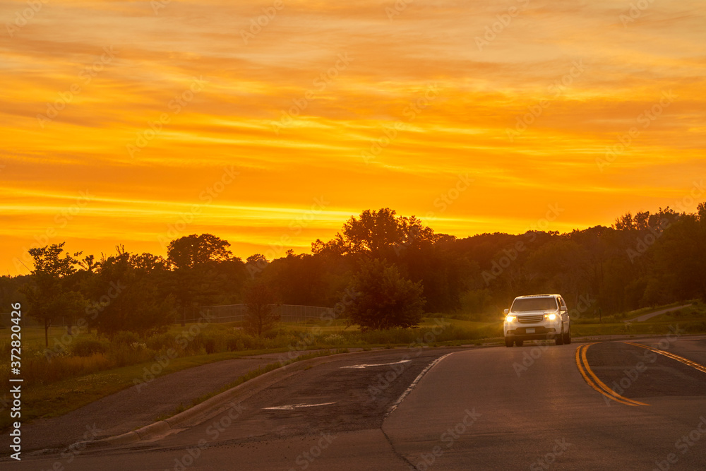 Headlights of car at night lighting the road at sunset's golden hour Headlights of car at night lighting the road at sunset's golden hour