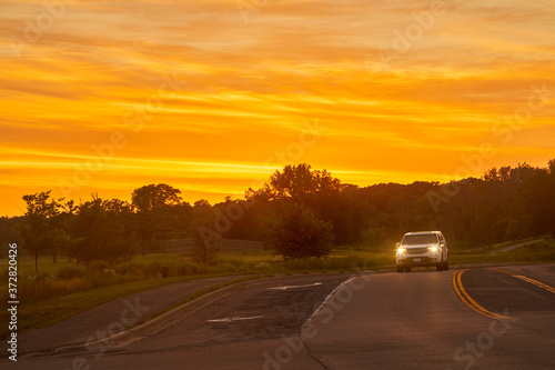 Headlights of car at night lighting the road at sunset s golden hour