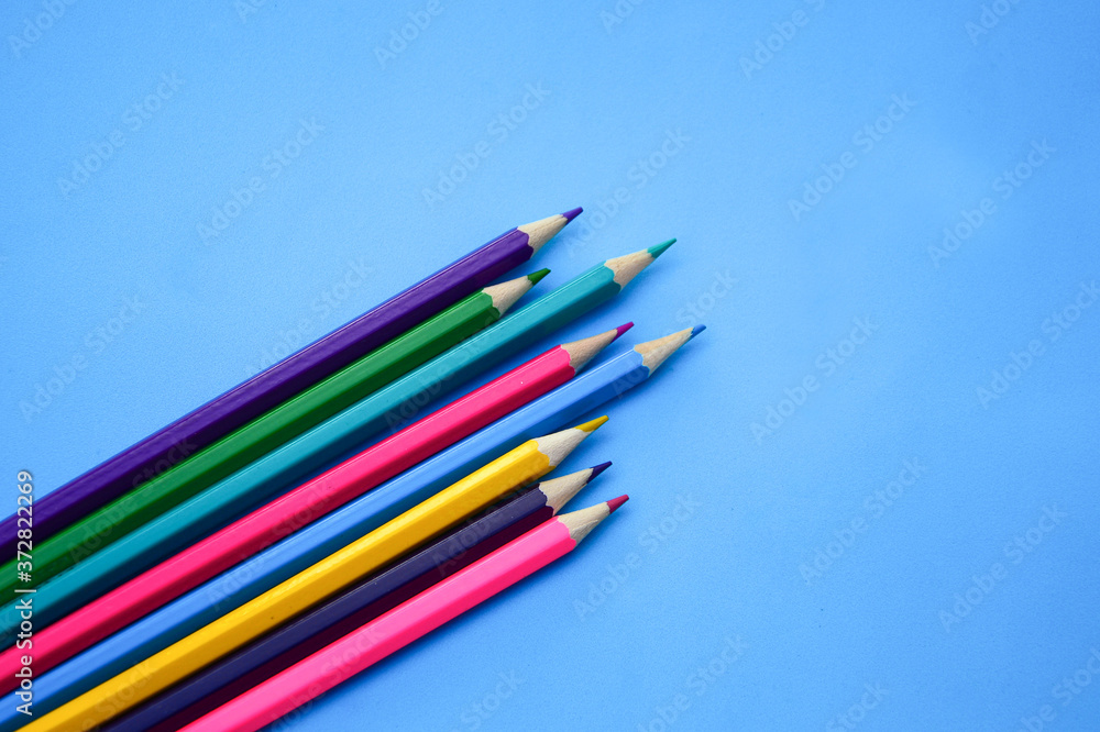 Colorful pencils by diagonally on blue background. School concept Colorful pencils by diagonally on blue background. School concept