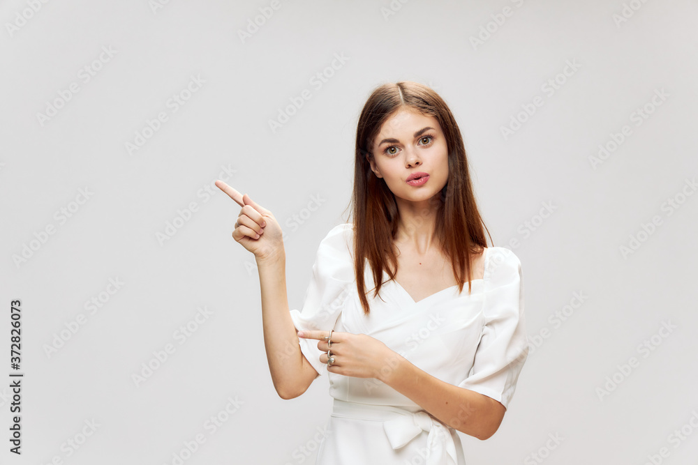 Woman with long hair gestures with her hands pointing to the top of a white dress Copy Space Woman with long hair gestures with her hands pointing to the top of a white dress Copy Space