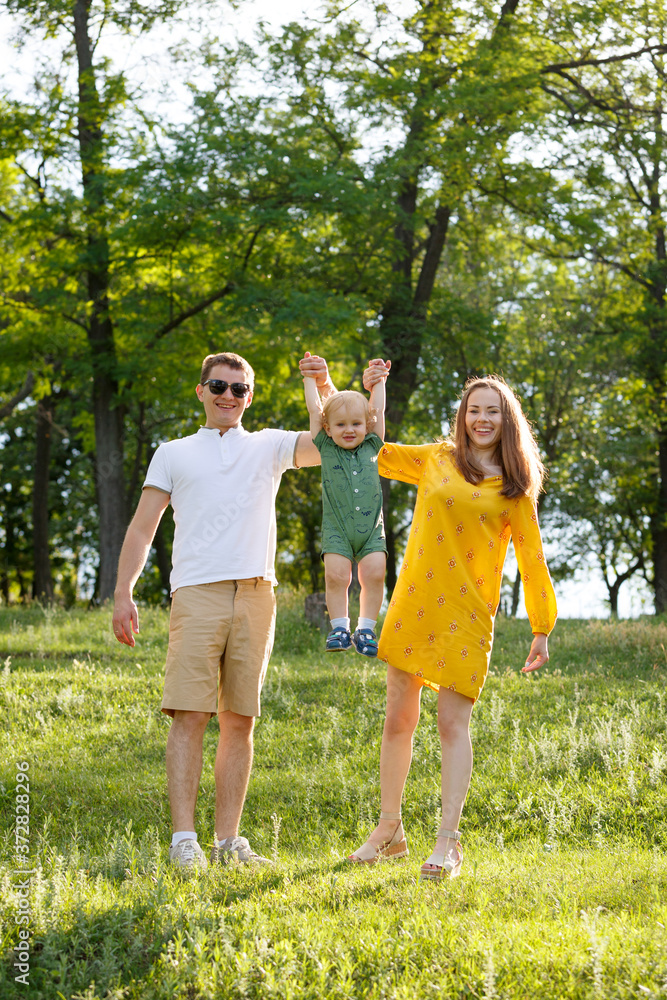 Fototapeta premium Family life. Parents play with their son on background of nature. Happy family leisure outdoors.