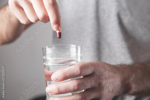 Man holding pill and a glass of water.