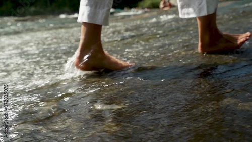 Slow motion of feet walking through the water in a river. photo