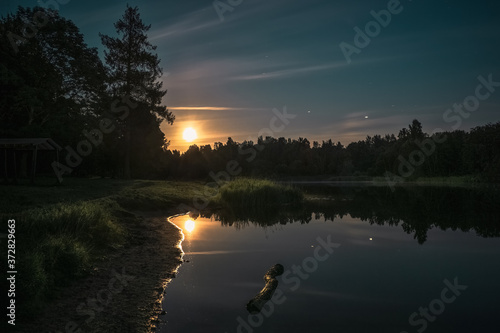 Night landscape with the reflection of the moon in the lake