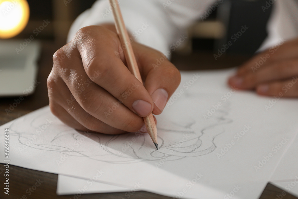 Man drawing portrait with pencil on sheet of paper at wooden table, closeup Man drawing portrait with pencil on sheet of paper at wooden table, closeup
