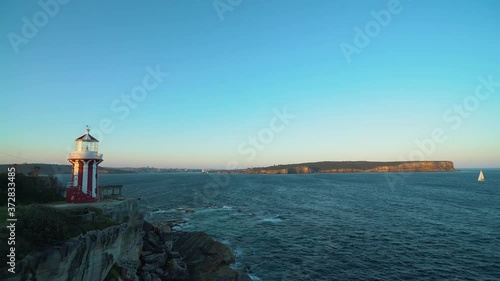 Calm ocean with stunning sunset and lighthouse in front. Small boat sailing by. Sydney, Australia photo